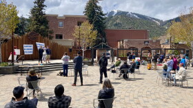 A spread-out crowd sits in a plaza in downtown in Ketchum to hear people speak about adorable housing challenges.