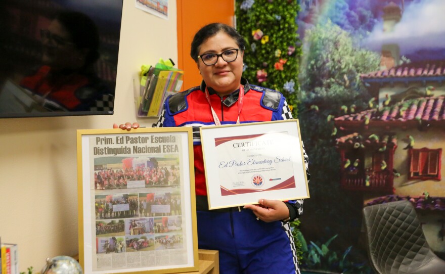 Principal Maritza Mares, dressed for the school's theme of "Racing Together, Winning as One" this year, shows off Ed Pastor Elementary's certificate of recognition as a 2024 National Distinguished School.