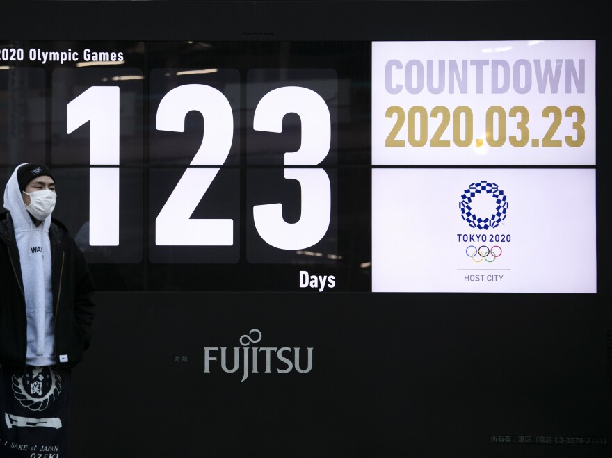 A man stands in front of a countdown display for the Tokyo 2020 Olympics and Paralympics in Tokyo, on Monday. Japan's Prime Minister Shinzo Abe acknowledged that a postponement of the crown jewel of the sporting world could be unavoidable. [Jae C. Hong / AP]
