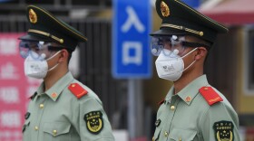 Paramilitary police officers wear face masks and goggles as they stand guard at an entrance to the closed Xinfadi market in Beijing on Saturday.
