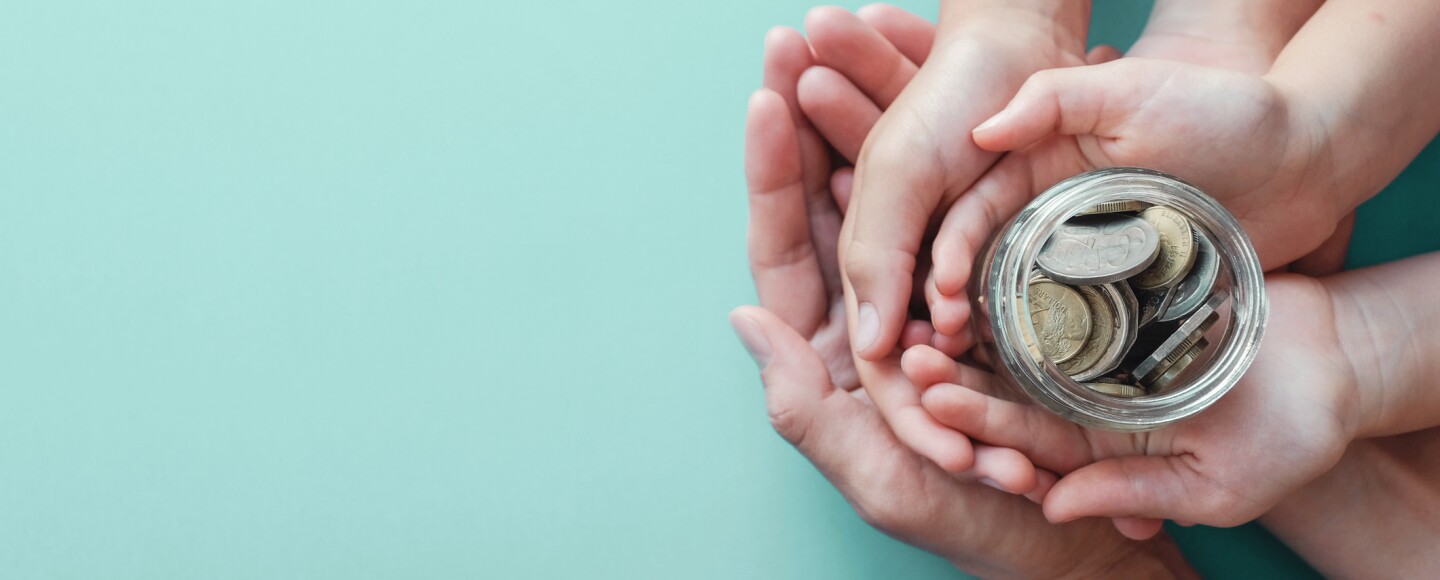 child and parent hands holding money jar, donation, saving, family finance plan concept