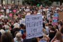 A large crowd outside the state capitol holding signs.