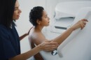 A medical provider guides a patient through the mammogram process.
