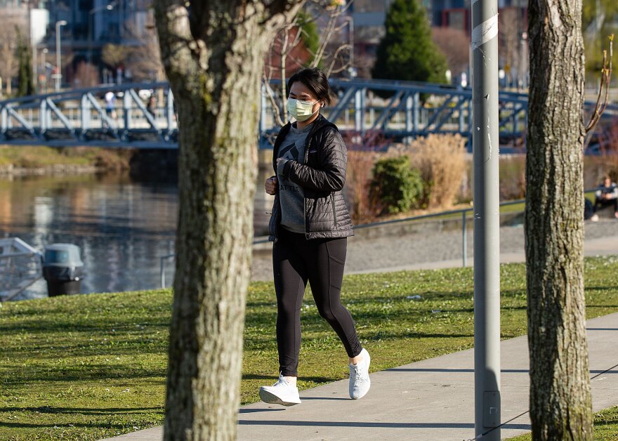 A jogger wearing a mask runs through Lake Union Park in Seattle on Thursday.