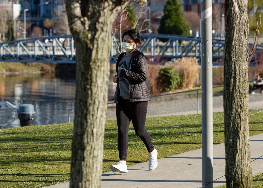 A jogger wearing a mask runs through Lake Union Park in Seattle on Thursday. 