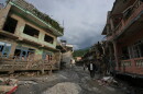 People walk along a street lined with damaged structures after flash flooding in the Devighat area of Nuwakot district in Nepal on Friday, Aug. 28, 2026.
