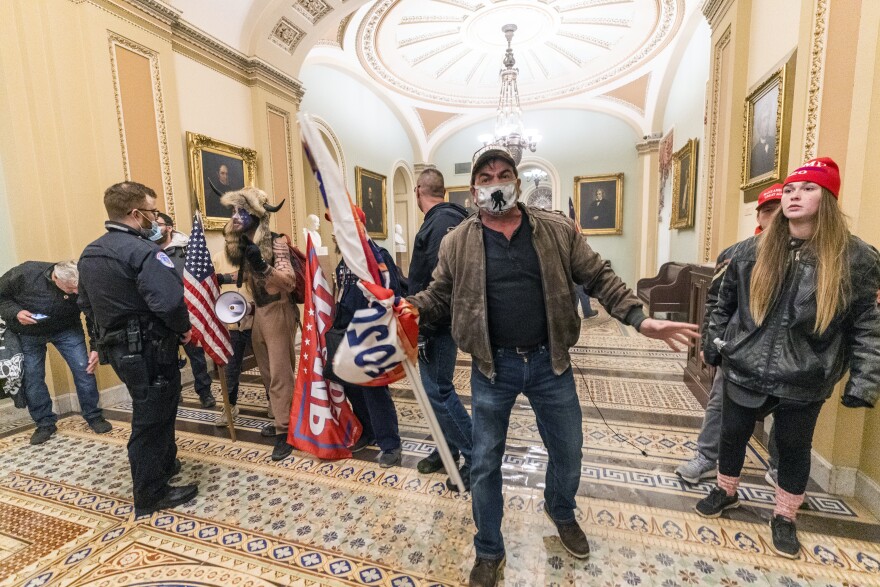 Supporters of President Donald Trump enter the Senate Chamber inside the Capitol, Wednesday, Jan. 6, with U.S. Capitol Police officers nearby.