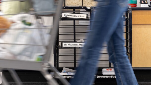 A grocery store shopper passes by a newsstand in Omaha where daily papers sit for sale on Oct. 8, 2025. The Omaha World-Herald and the Lincoln Journal-Star will no longer print a Monday edition starting in early November.