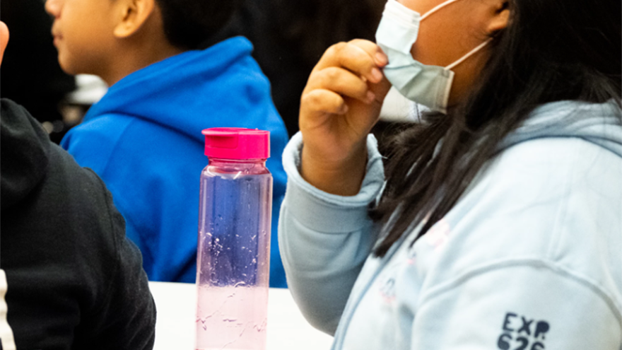 A student sits next to a water bottle in the cafeteria at Maureen Joy Charter School in Durham, North Carolina. (Photo by Cornell Watson for WUNC)