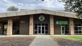 A single story pale brown building, with glass doors. 