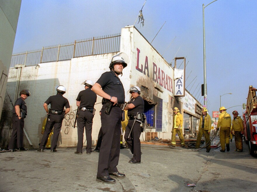 Los Angeles police officers in riot gear stand guard at a grocery store that had been burned down near downtown Los Angeles on April 30, 1992.