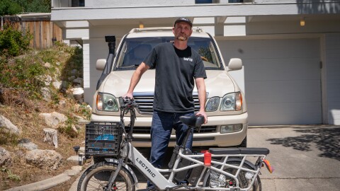Kerry Simon stands with his bike in front of his four wheel drive truck. He says being a car enthusiast has made his moral dilemma over using gas all the more harder.