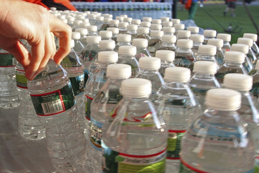 A hand reaches for one in a collection of plastic water bottles.