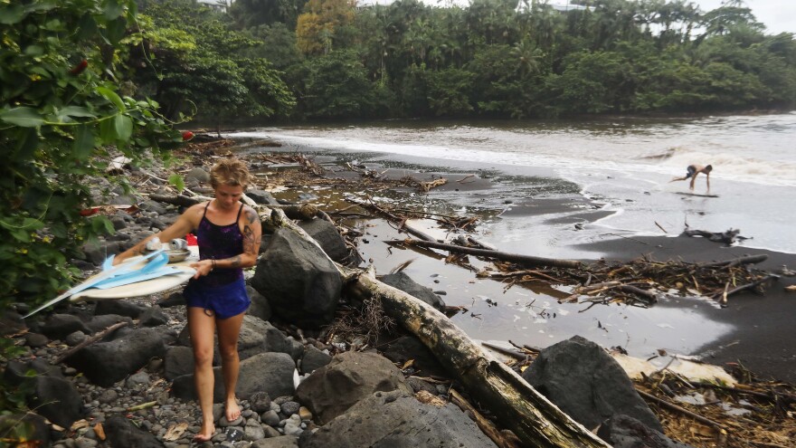 A surfer leaves the beach at Honoli'i Beach Park in Hilo, Hawaii, walking through the remains of trees that were swept away by floodwaters from Hurricane Lane. Now a tropical storm, Lane brought heavy rains to Hawaii before it weakened.