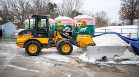 A front end loader picks up solar salt to put into the brine mixer at the Cambridge Public Works yard at Danehy Park. (Robin Lubbock/WBUR)