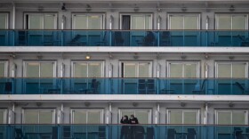 Passengers wearing face masks look out from their cabin on the Diamond Princess cruise ship in quarantine due to fears of COVID-19. (Philip Fong/AFP/Getty Images)