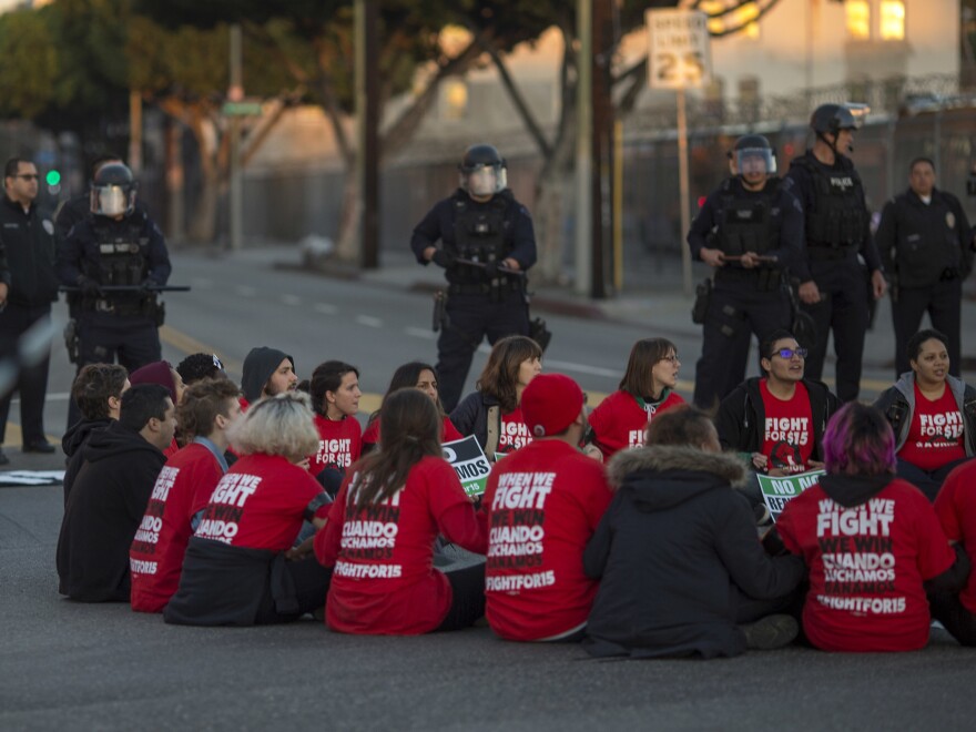 Police surround striking McDonald's workers sitting in an intersection in Los Angeles, demanding a $15 per hour wage and union rights during nationwide 'Fight for $15 Day of Disruption' in November 2016.