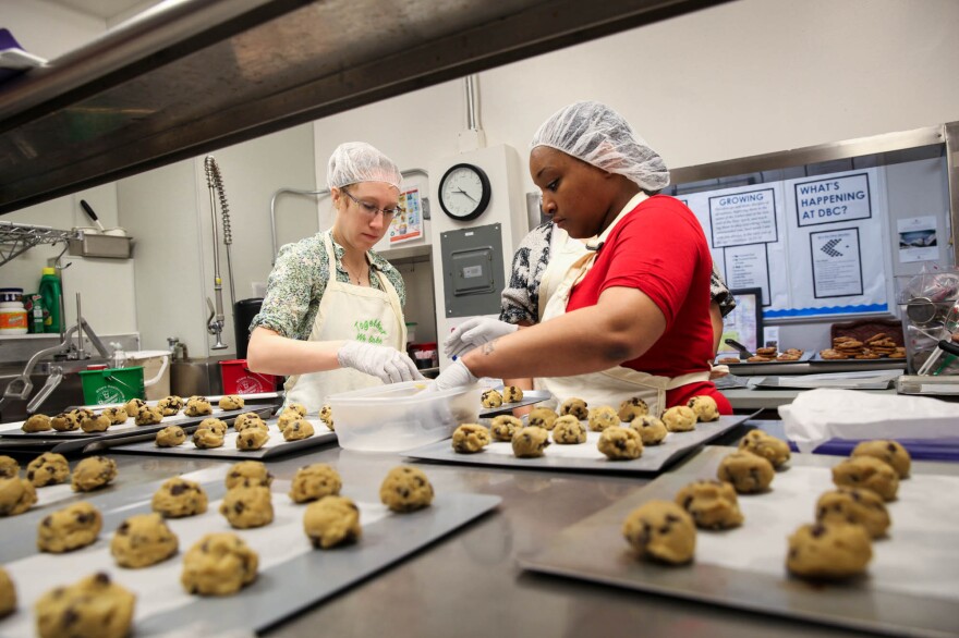 Elizabeth Bennett, director of partnerships for Together We Bake, and Nikki Yates, program participant, place cookie dough they've just made onto baking sheets.