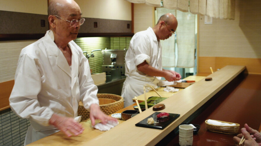 Jiro Ono (left) owns and runs a celebrated sushi restaurant in a Tokyo basement. His oldest son, Yoshikazu, waits to take over the world-famous family business.