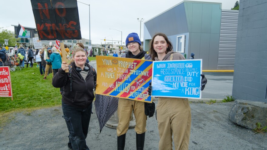 Lillian Wright (right) poses with her twin sister (center) with handmade signs.