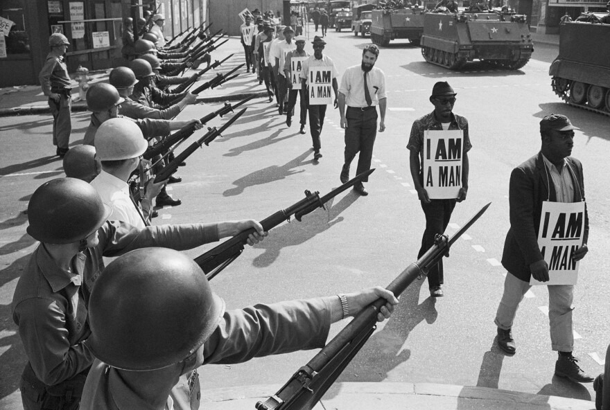 U.S. National Guard troops block off Beale Street as civil rights marchers wearing placards reading, "I AM A MAN" pass by on March 29, 1968.