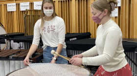 Meredith Conklin (left) and Elizabeth Humphrey (right) play a drum called a Timpani that is covered in a sheet of bubble wrap.