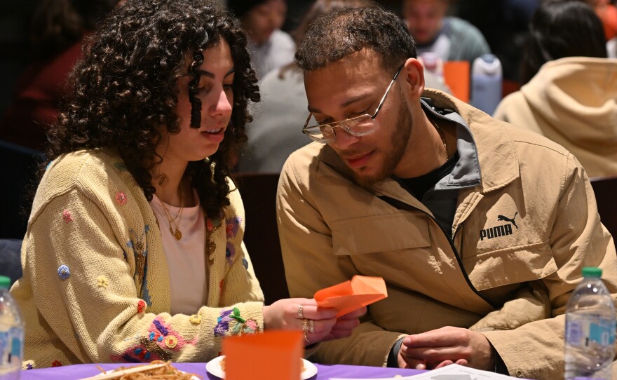 Senior Ashley Paulino teaches alumni, Luis Vasquez, how to make an origami heart during the Lunar New Year celebration at the University of Scranton.
