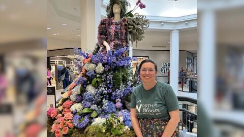 A florist stands next to a mannequin filled with a floral display. 