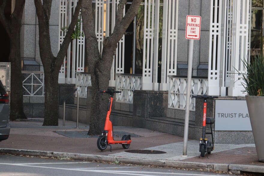 Two scooters parked under a no parking sign. 