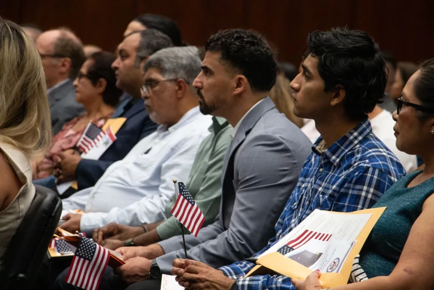 Josue Carranza, second from right, holds an American flag while listening to U.S. District Judge Thomas M. Durkin at an Aug. 18, 2026, naturalization ceremony in Chicago.
