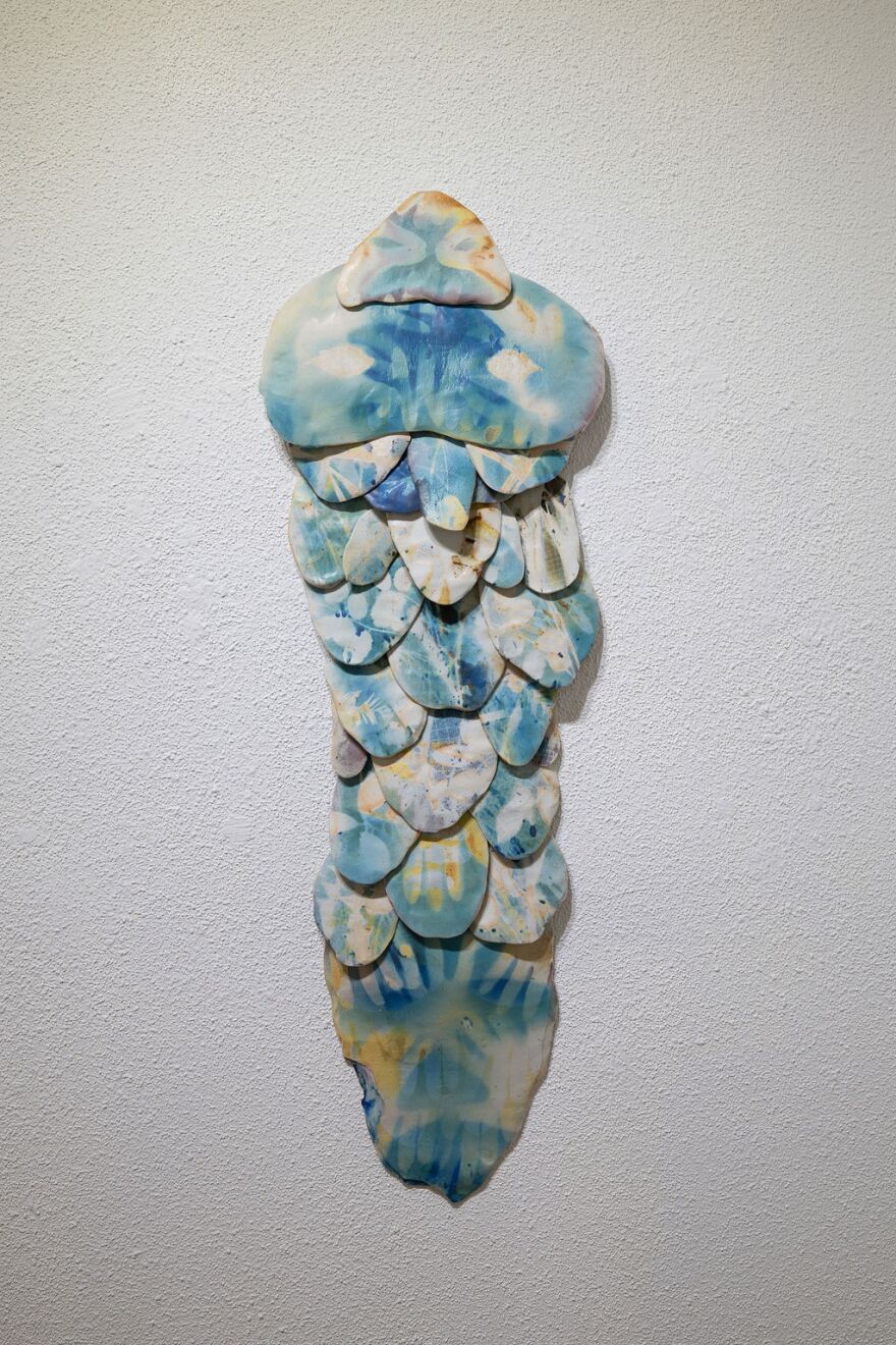 A sculpture that is blue, white, and yellow that looks like fish scales.