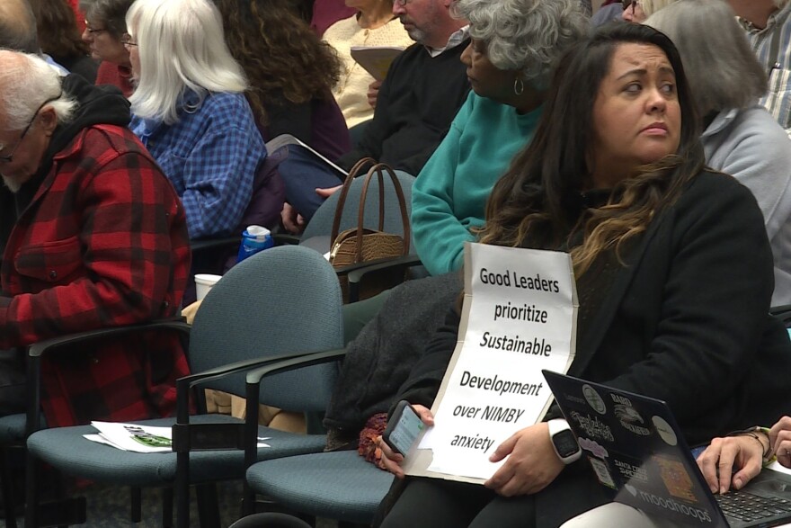 Many people in favor of multiplex housing who came to the meeting brought signs to hold while public comment was being made.