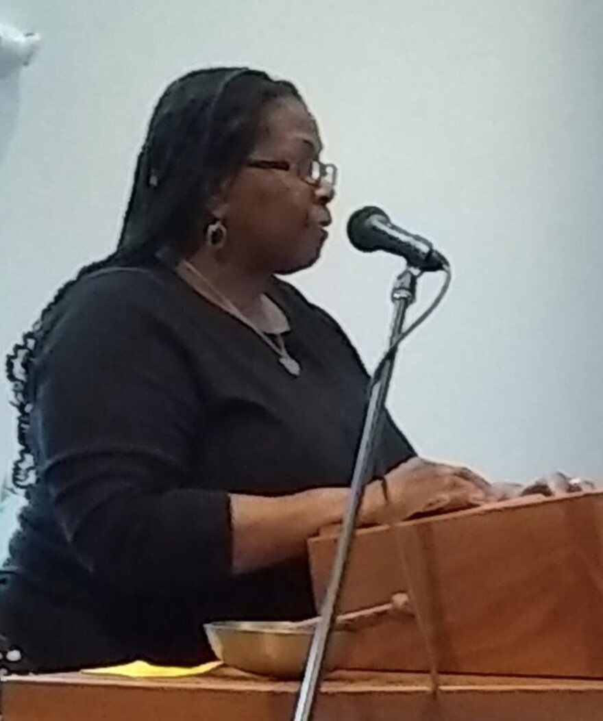 Nanette Massey, wearing black, speaks at a microphone