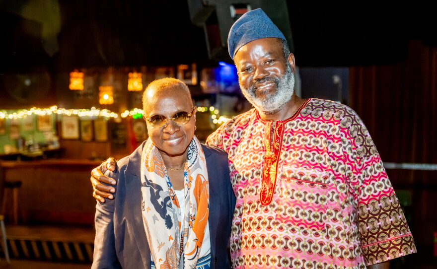 A man and woman stand smiling.