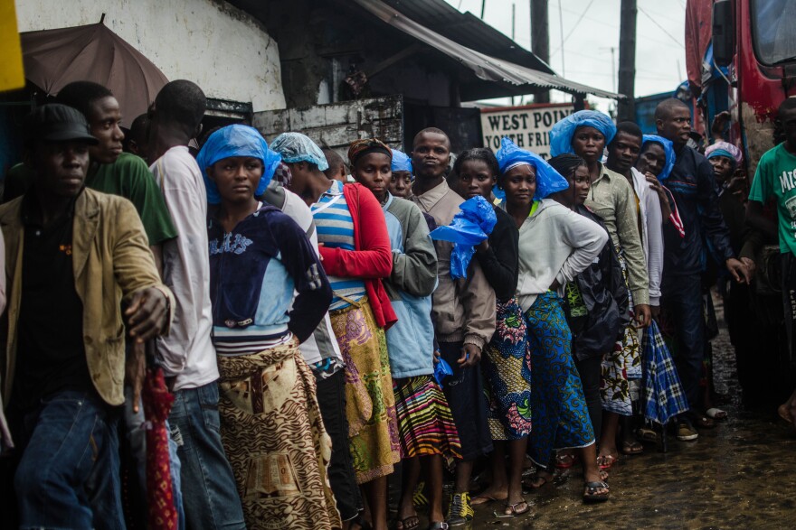 Recovering from the toll of the Ebola quarantine, residents of the West Point slum in Monrovia line up for food.