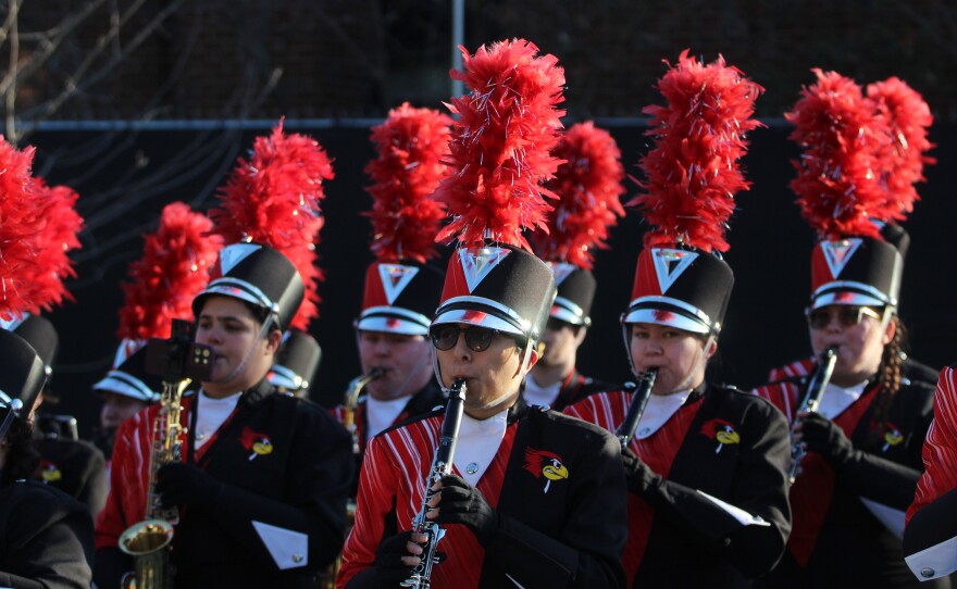 Fans and marching band members greet ISU football players and coaches