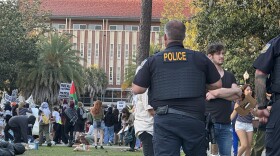 An unidentified University of Florida campus police officer watches over about 50 pro-Palestinian protesters who demonstrated on campus Thursday, April 25, 2024, for a second consecutive day. There was no violence or police response – a contrast to what was happening at some other college campuses around the U.S.