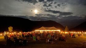 A crowd gathers in front of a tent for an evening concert at the AMC Highland Center.