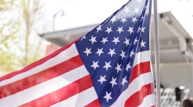 An American flag with the sun behind it