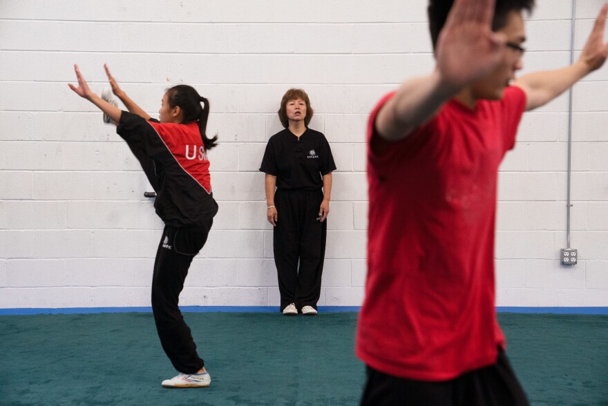 Zhang coaches from the sidelines as students stretch before practice.