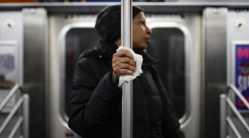 A subway customer uses a tissue to protect her hand while holding onto a pole as COVID-19 concerns drive down ridership, Thursday, March 19, 2020, in New York. (John Minchillo/AP Photo)