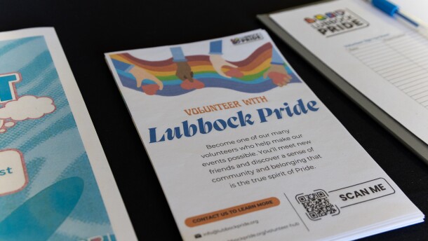 A photo of various pamphlets and sign-ups on the LubbockPRIDE table at the resource fair. Centered is a handout that says 'Volunteer with Lubbock Pride: Become one of our many volunteers who help make our events possible. You'll meet new friends and discover a sense of community and belonging that is the true spirit of Pride.
