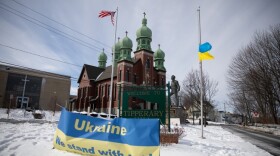 Signs, flowers, and flags fill a small traffic barrier in front of St. John the Baptist Ukrainian Catholic Church Syracuse, NY, Feb. 28th 2022.
