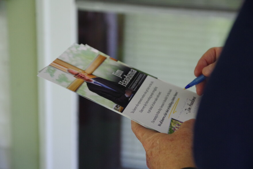 A zoomed in picture of a campaign flyer for Democratic candidate for Michigan's 44th house district Jim Haadsma. The flyer is held in one hand, as the person holding it writes a note on the flyer with a pen.