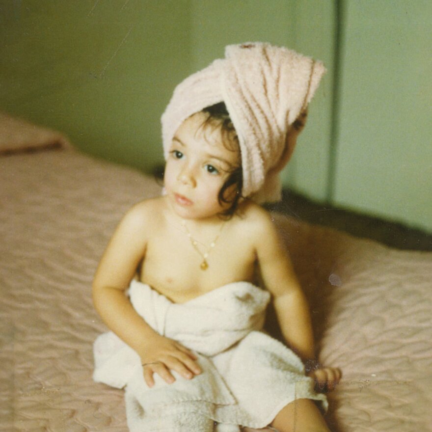 A young child wrapped in two bath towels.