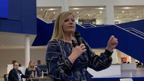 Woman in blue dress, standing with microphone in right hand