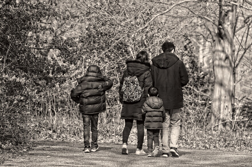Black and white image of family walking on a trail with their coats on and it looks like the weather is chilly or cold.