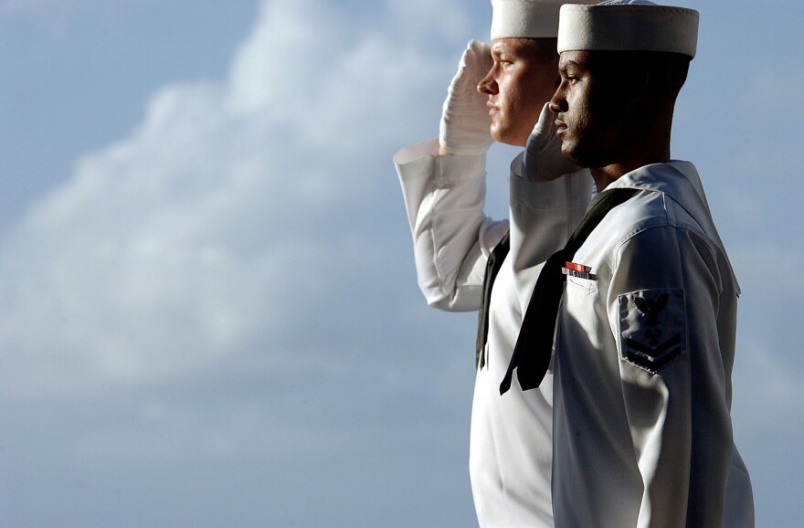 Navy sailors salute the American flag.