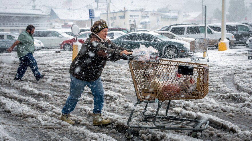 As snow fell in Rapid City, S.D., Friday Brenda Nolting took groceries to her car. An early snow storm swept through Wyoming and western South Dakota, dropping more than two fee of snow in some areas.