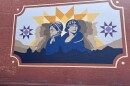 A mural of two women painted in blue on a red brick wall.